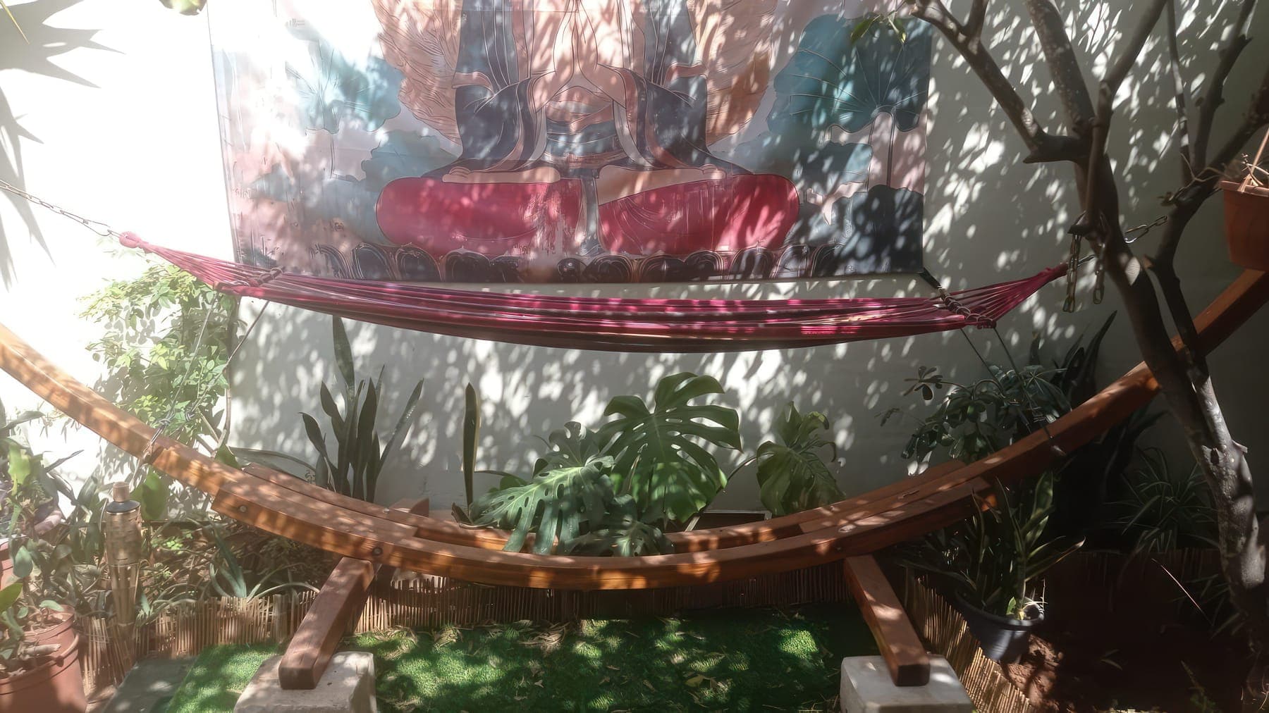 A hammock in dappled shade beneath a meditating figure
